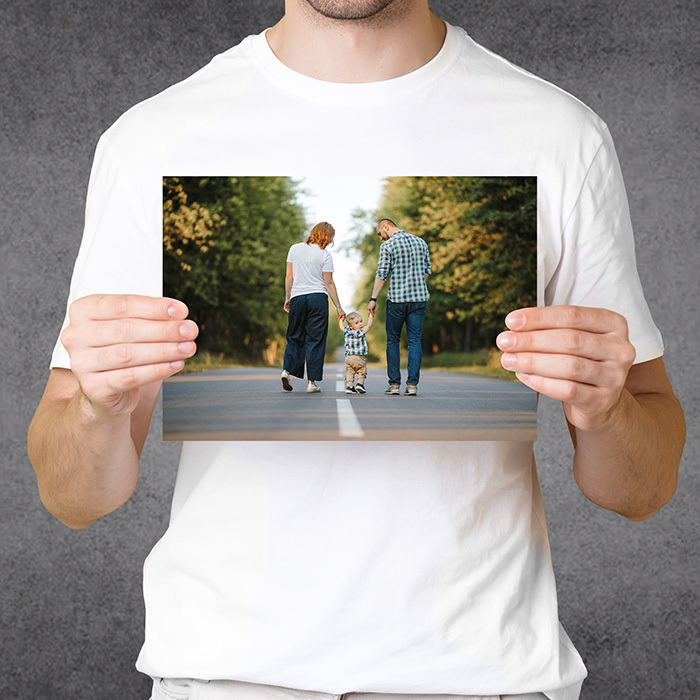 Handsome young male tourist in summer hat smiling holding blank piece of paper for your sign standing over yellow background